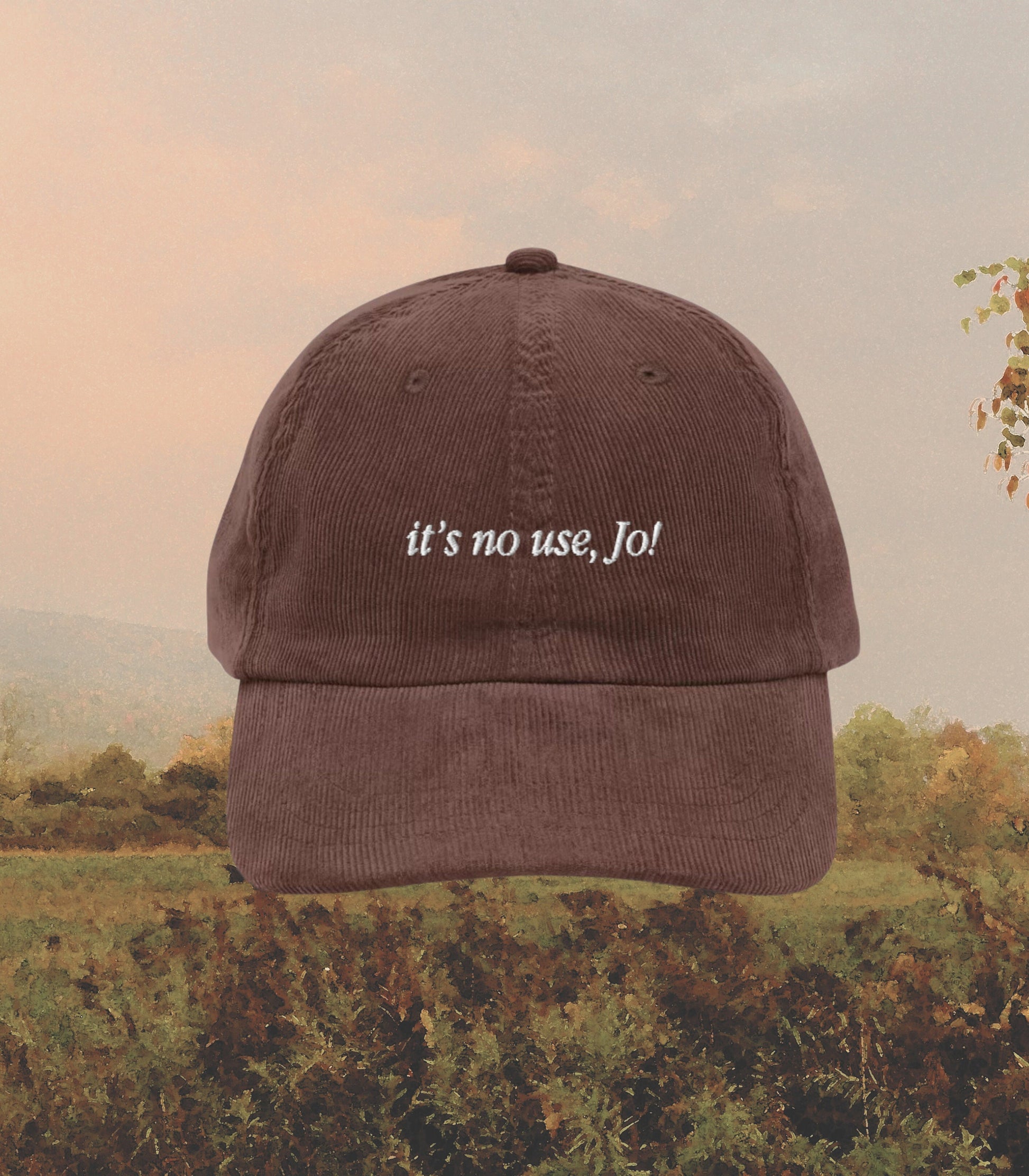 May include: A brown corduroy baseball cap with the text "it's no use, Jo!" embroidered in white on the front.