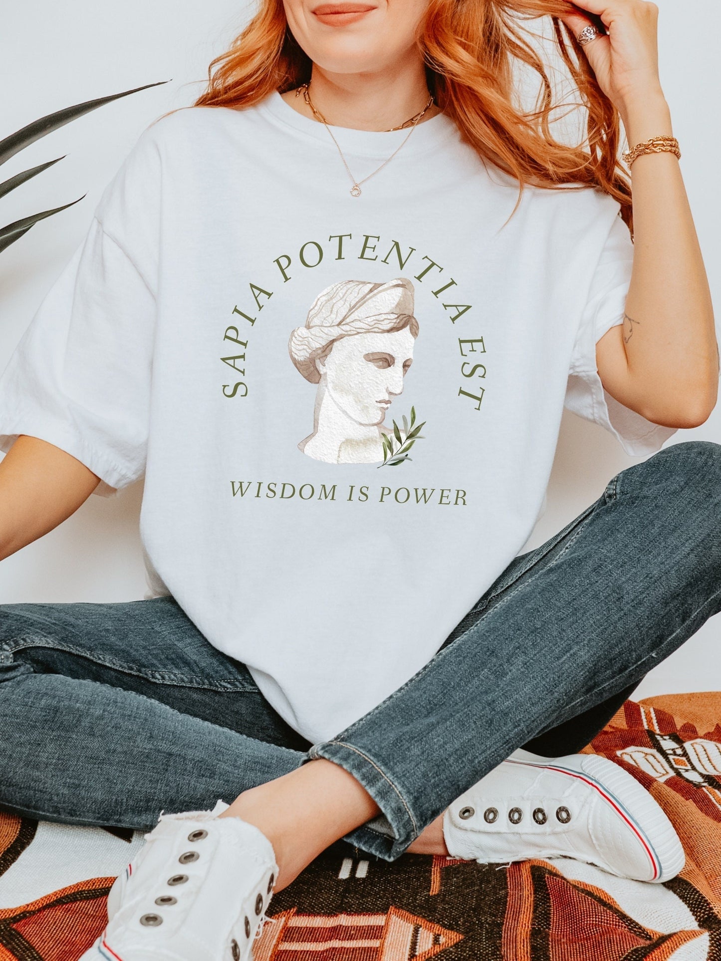 May include: White t-shirt with a green graphic of a woman's bust with the text "SAPIA POTENTIA EST" and "WISDOM IS POWER" below.